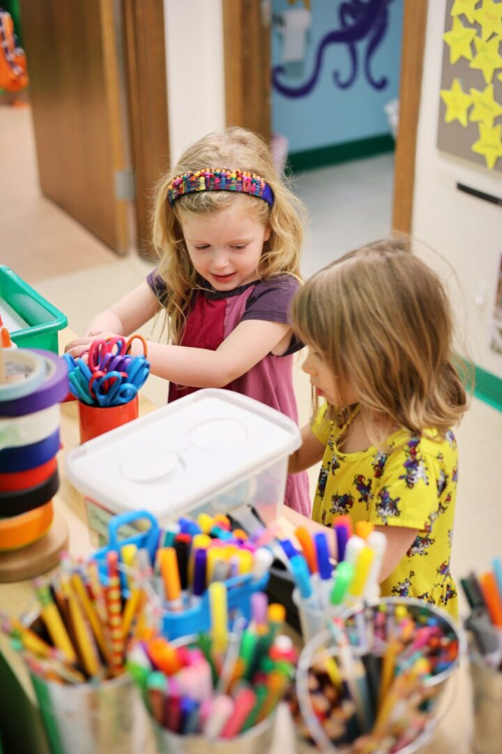 two young girls in front of art supplies