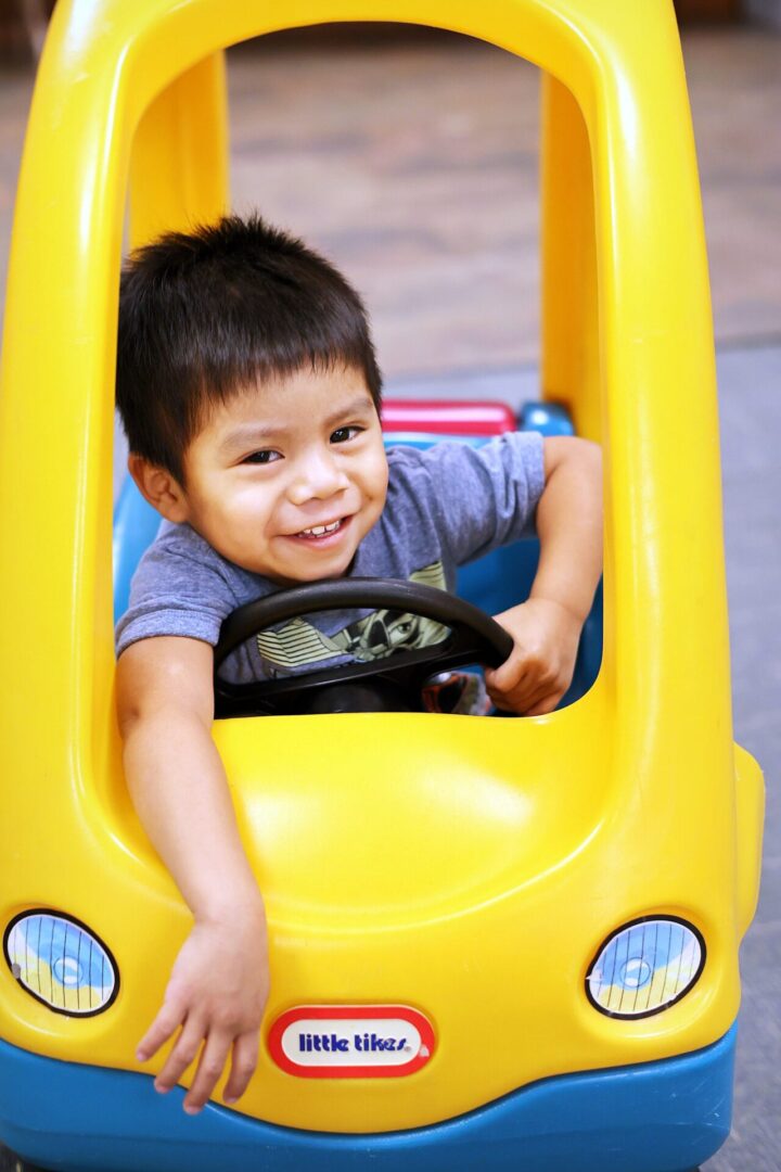 a young boy inside a big toy car
